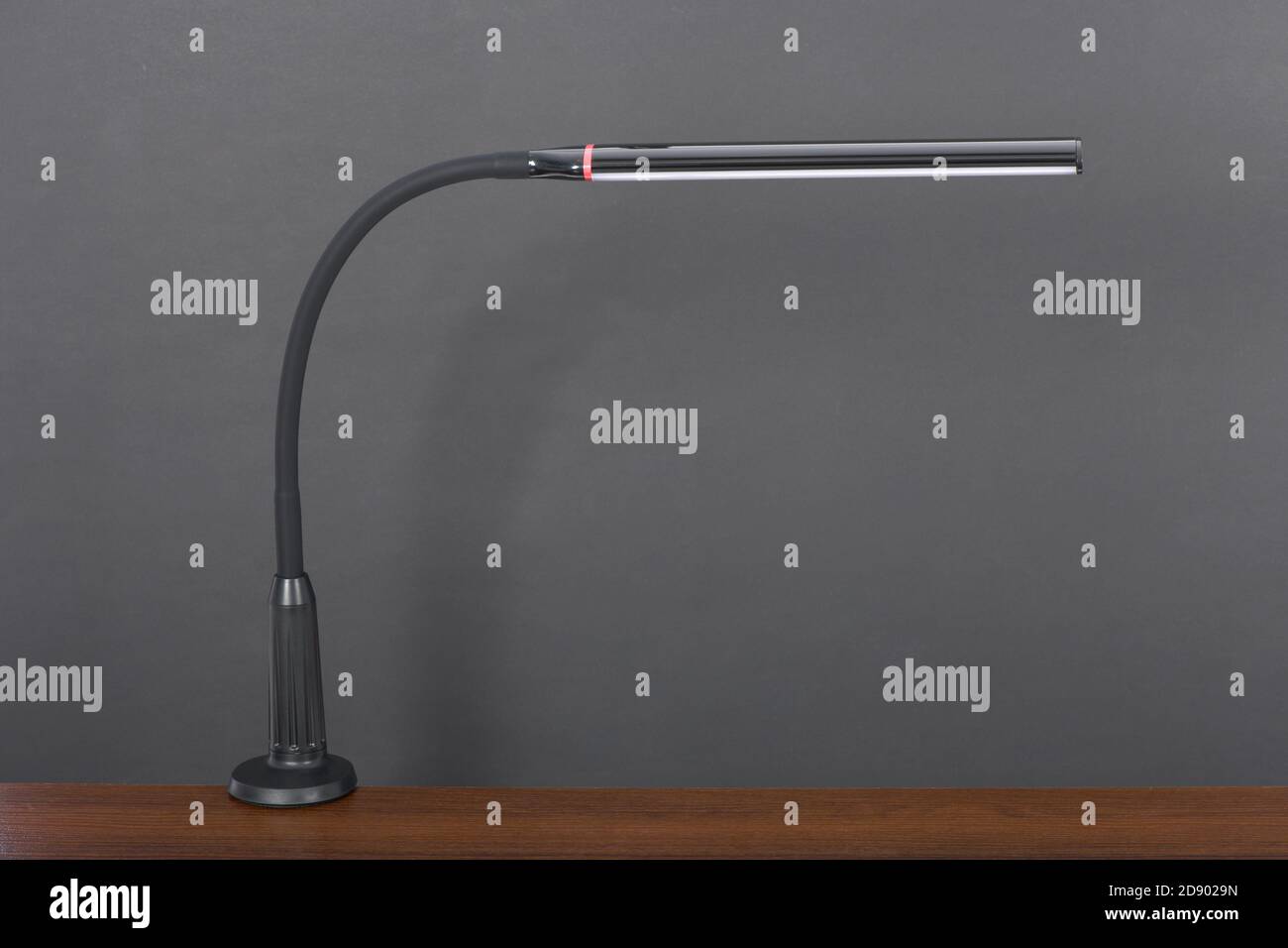 Modern black flexible desk lamp isolated on black background. High resolution photo. Full depth of field. Stock Photo