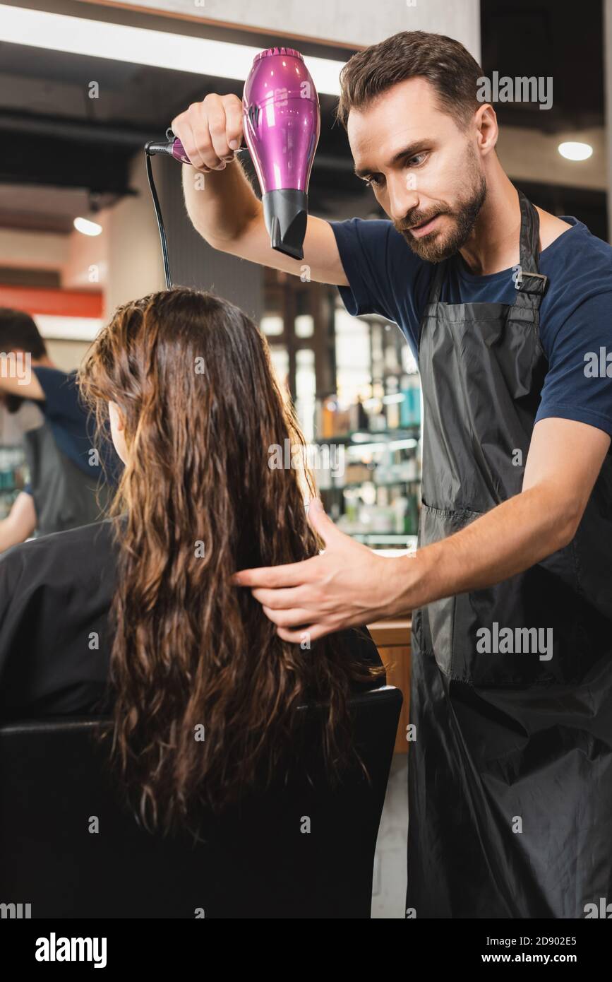 young hairdresser in apron drying hair of woman Stock Photo - Alamy