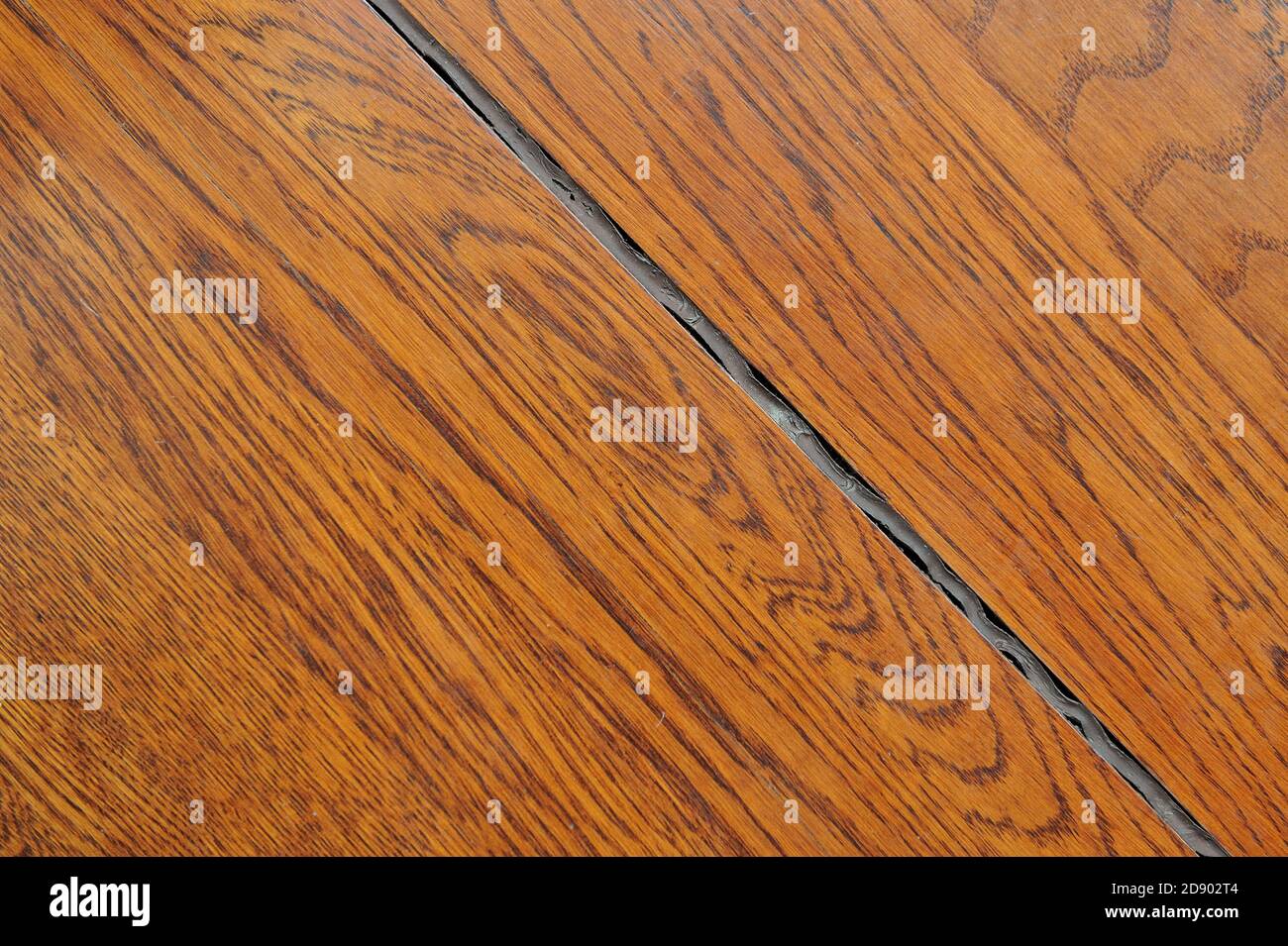 Crevice in the wood floor and aged silicone sealant Stock Photo