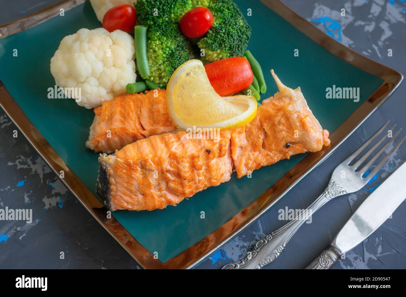 diet serving of salmon with lemon, broccoli and vegetables. Two pieces ...