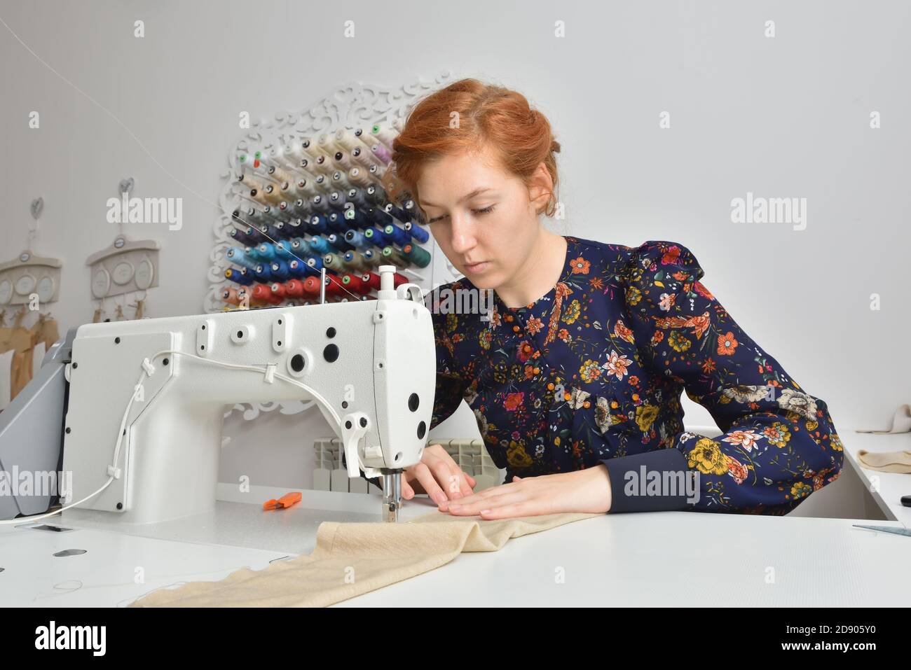 Young woman working on a sewing machine in a sewing studio Stock Photo