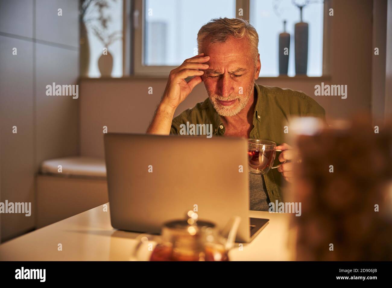 Senior man having a headache from working on laptop Stock Photo