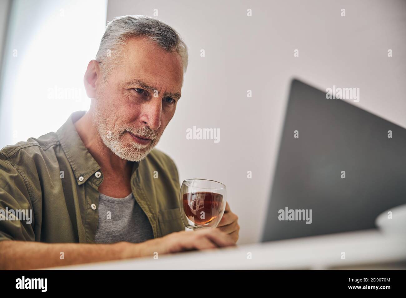 Concentrated aged man looking at a laptop screen with concern Stock Photo
