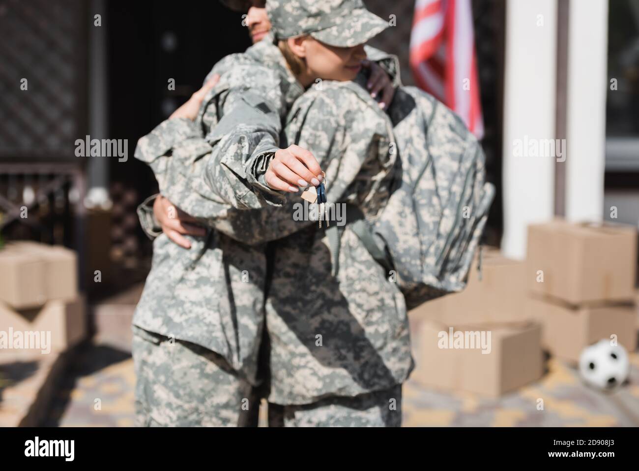 Military couple embracing and holding keys with blurred house and ...