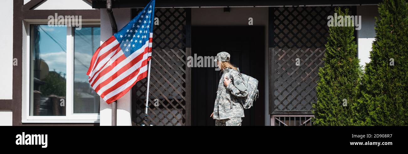 Military servicewoman with backpack leaving house, standing on threshold, banner Stock Photo