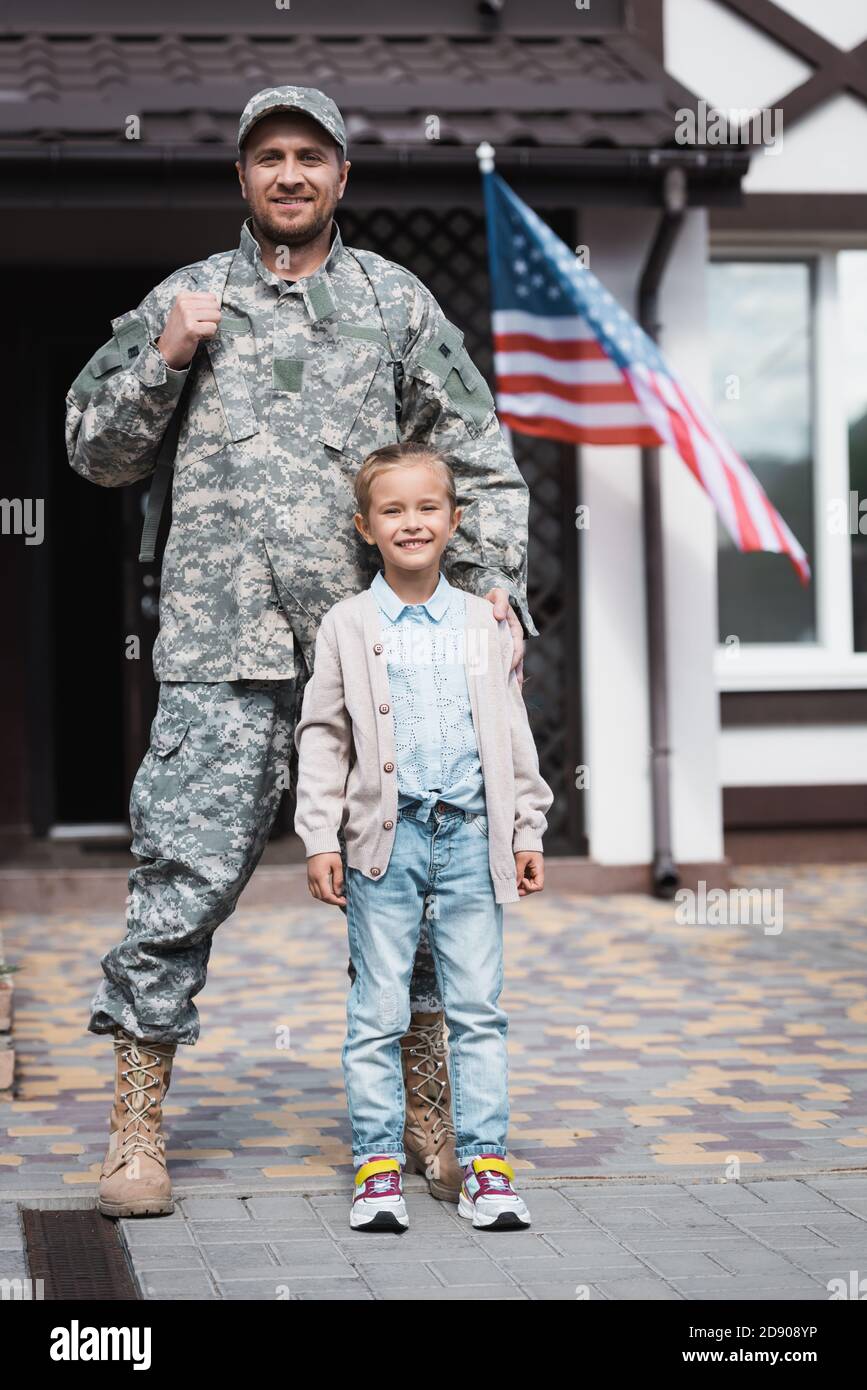 Front view of father in military uniform standing with daughter on blurred background Stock Photo