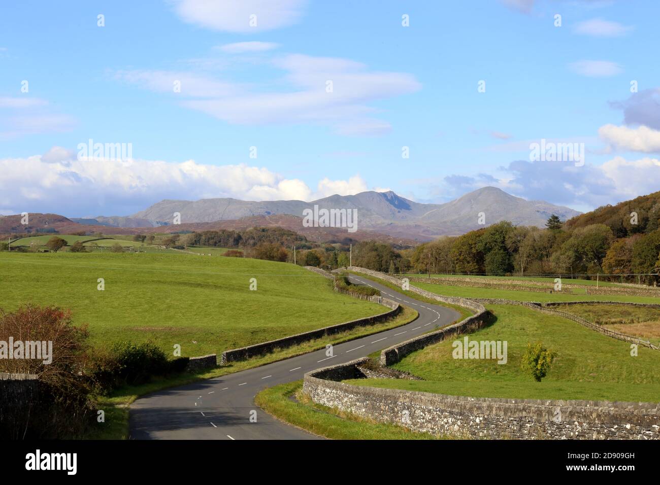 Low road to the High Lands. South Cumbria road twists and turns towards the Coniston Old Man range in the Cumbrian mountains of Northern England. Stock Photo
