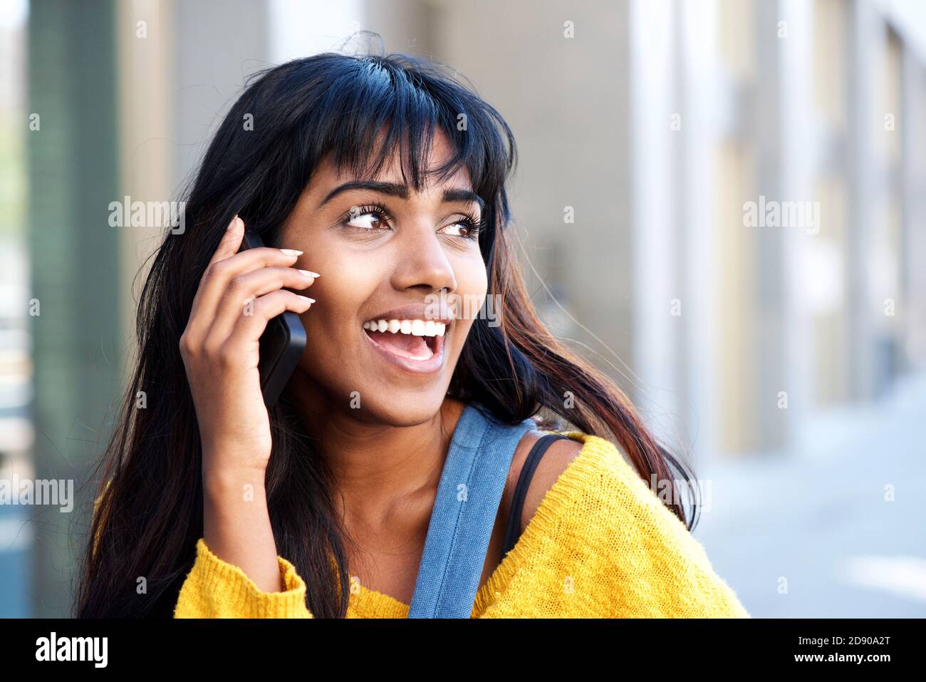 Portrait of cool young Indian woman talking on mobile phone outside in ...