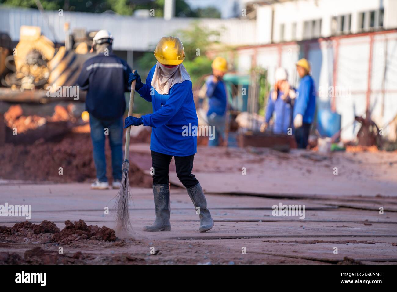 Construction worker sweepers soil debris with brush broom In the construction site Stock Photo