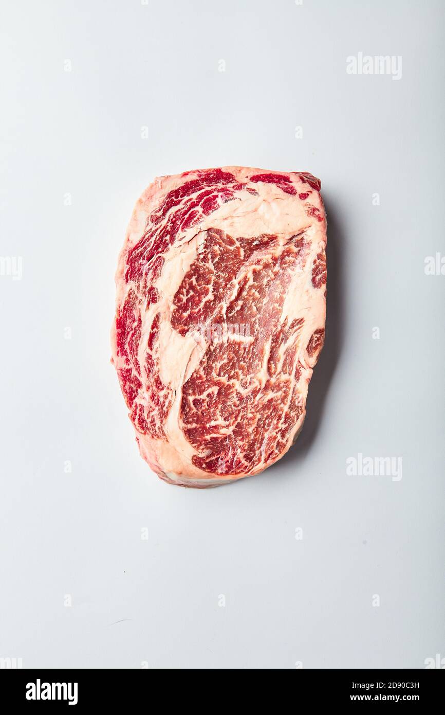 Rrib eye steak of marbled grain-fed beef lies on a white background. Marbled beef top view Stock Photo
