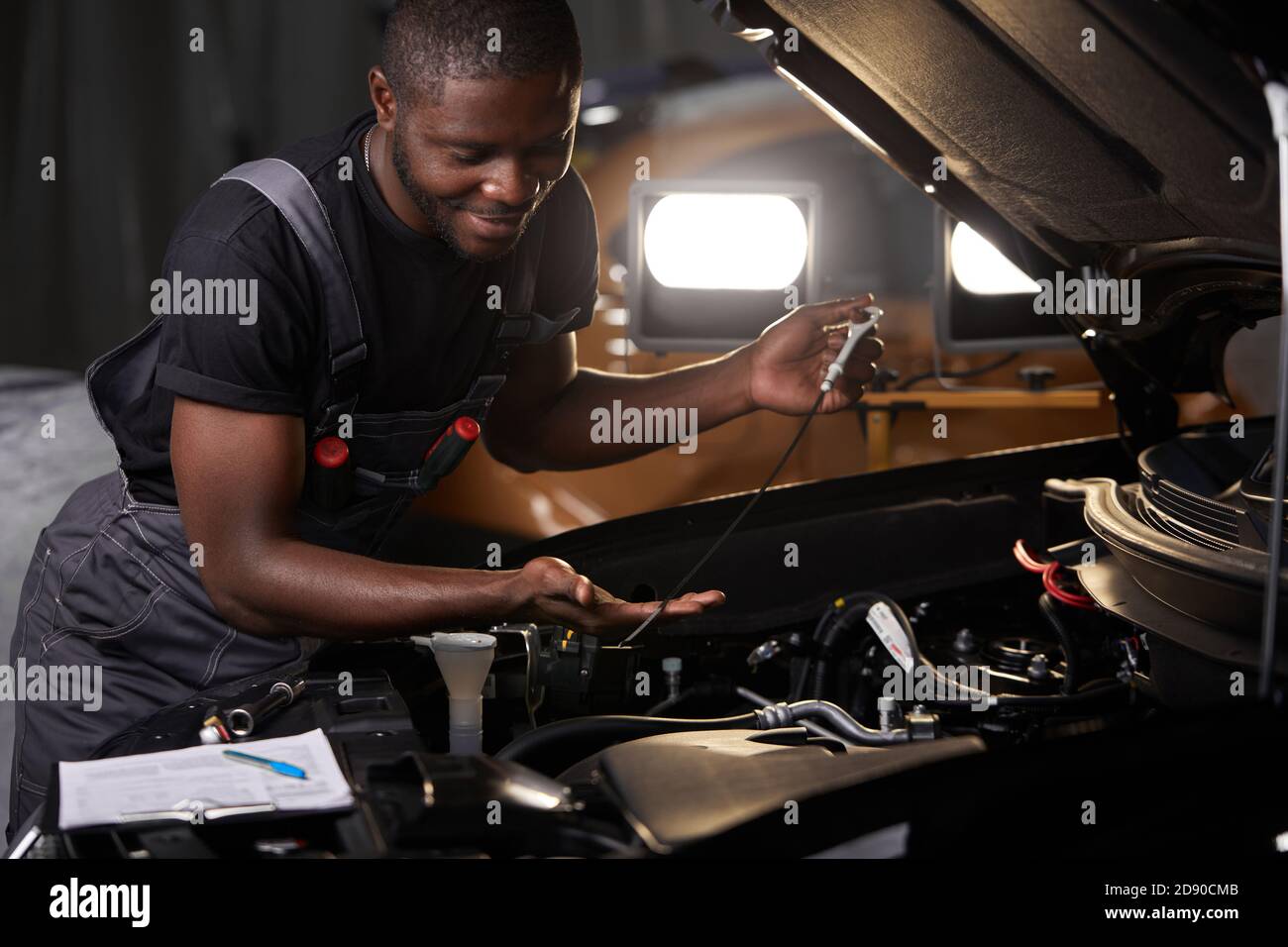 professional car mechanic is examining engine under the hood at auto