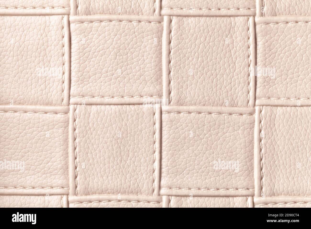 Texture of beige leather background with square pattern and stitch, macro. Abstract backdrop from modern decorative light brown textile with geometric Stock Photo