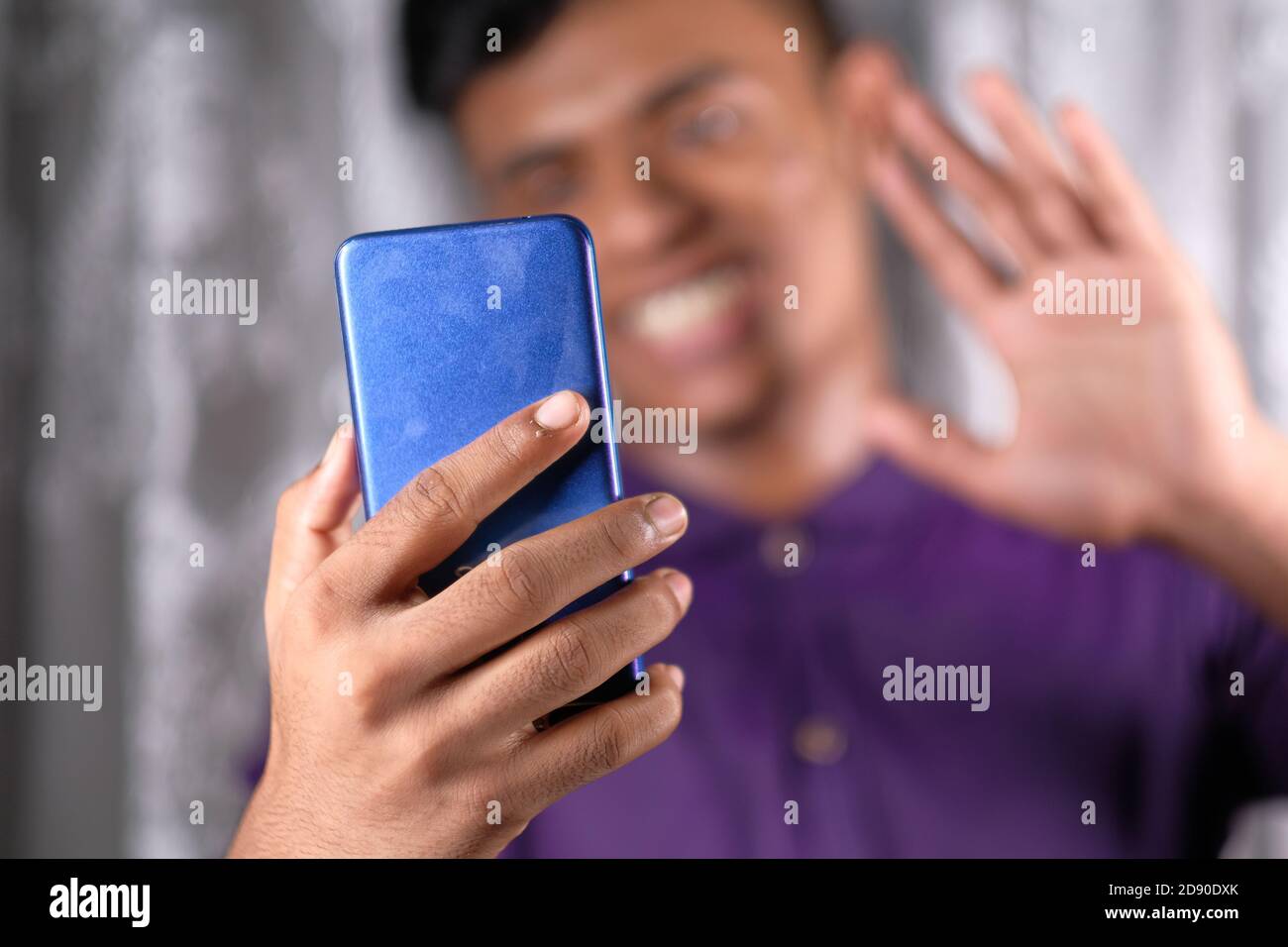 Smiling young man using his phone to make a video call Stock Photo