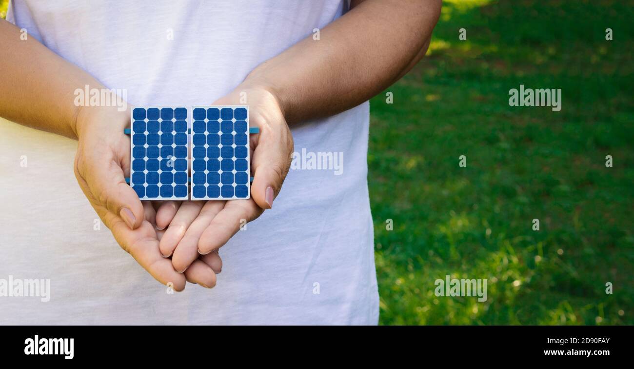 Holding solar energy photovoltaic panel at a green natural background - Concept Image of Sustainable Resources Stock Photo