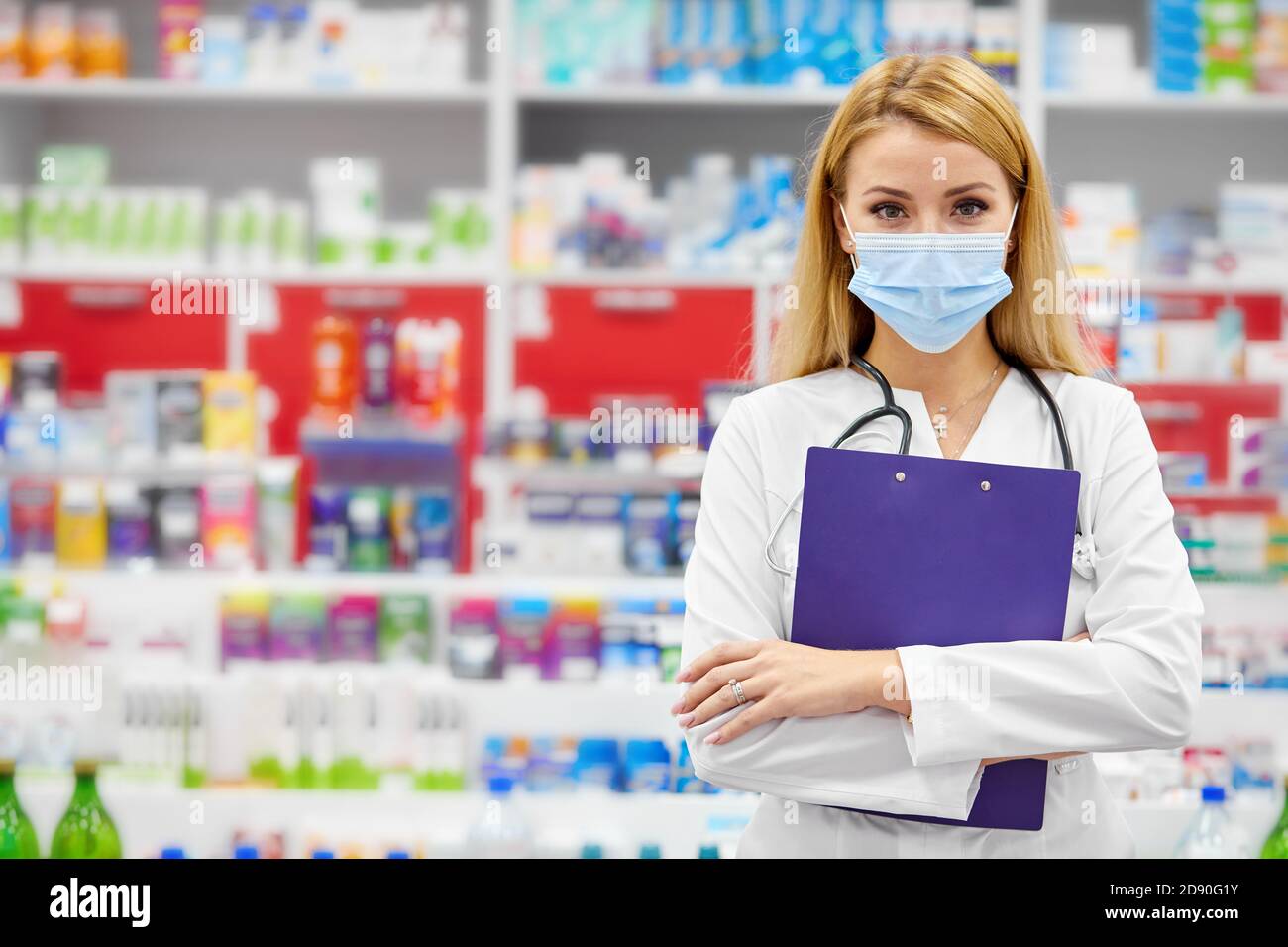 portrait of beautiful young woman pharmacist in uniform at modern drugstore, attractive diligent druggist at work, ready to help customers Stock Photo