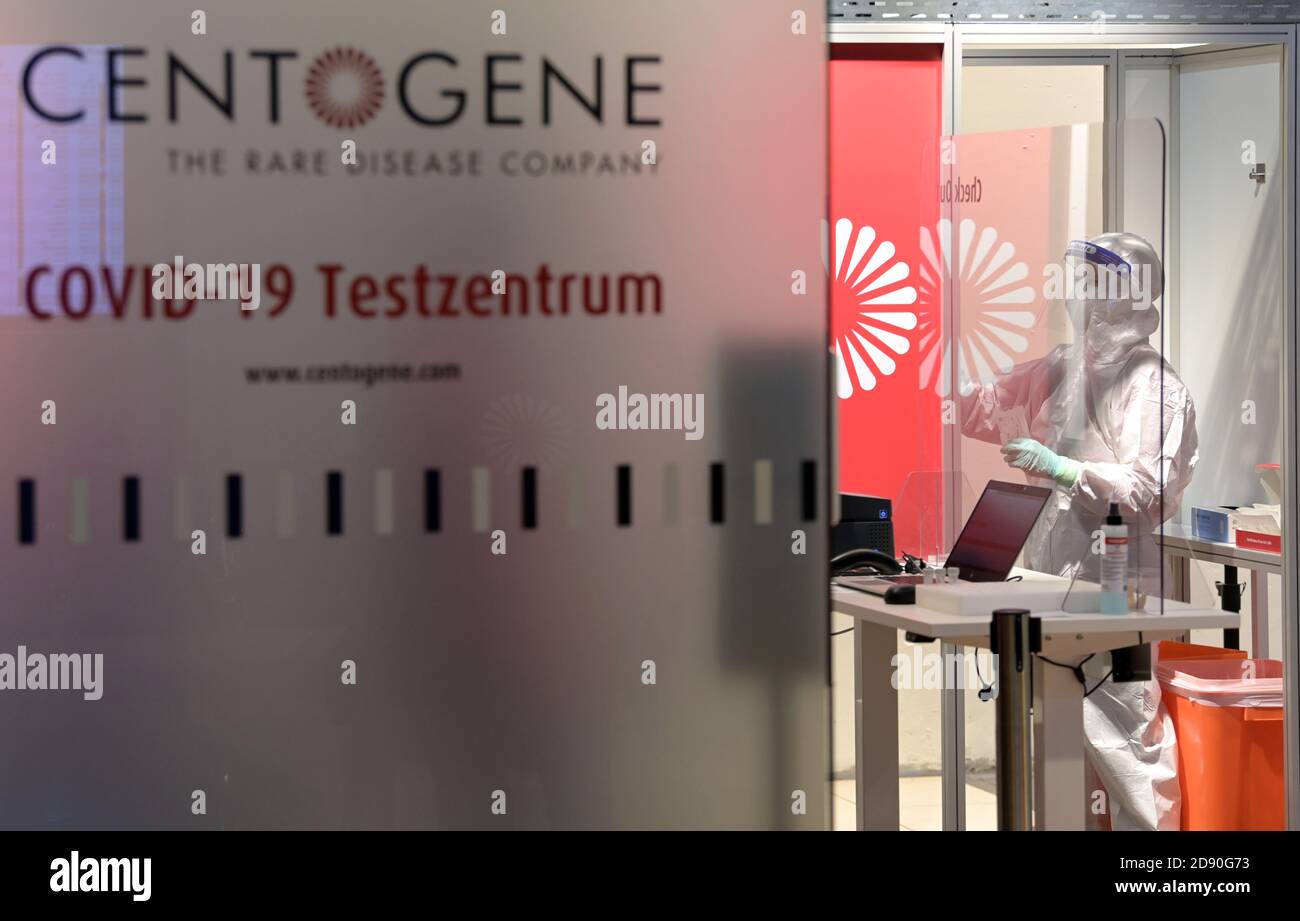 Berlin, Germany. 02 November 2020, Brandenburg, Schönefeld: At Berlin Brandenburg Airport Willy Brandt (BER) in the Centogene Covid 19 test center, a swabber in a white protective suit takes a sample from a patient standing behind a red privacy screen. The new test centre on level 0 in Terminal 1 is operated in cooperation with the airport company and the Malteser Hilfsdienst. Photo: Soeren Stache/dpa-Zentralbild/dpa Credit: dpa picture alliance/Alamy Live News Stock Photo