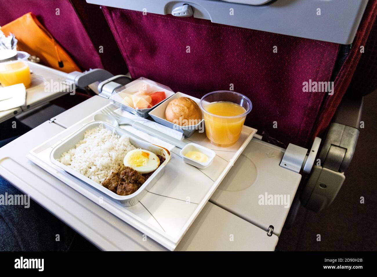 Basic inflight meal consisting rice, egg, beef curry, bread, juice ...