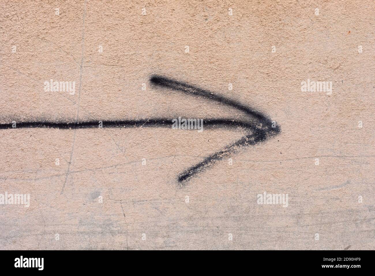 Black arrow painted on a beige wall. Stock Photo
