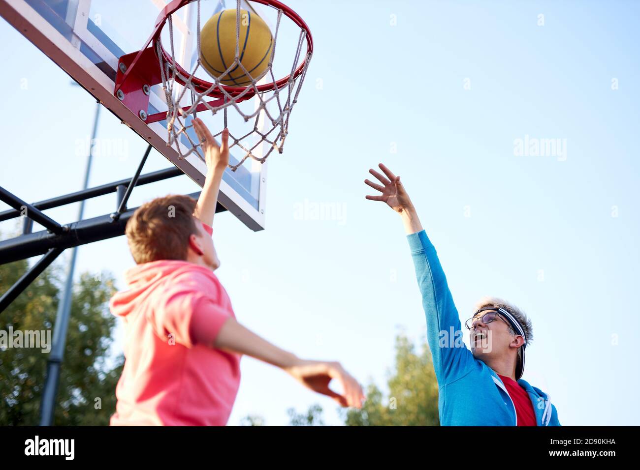 teens boys shooting basket and playing basketball at playground, lower