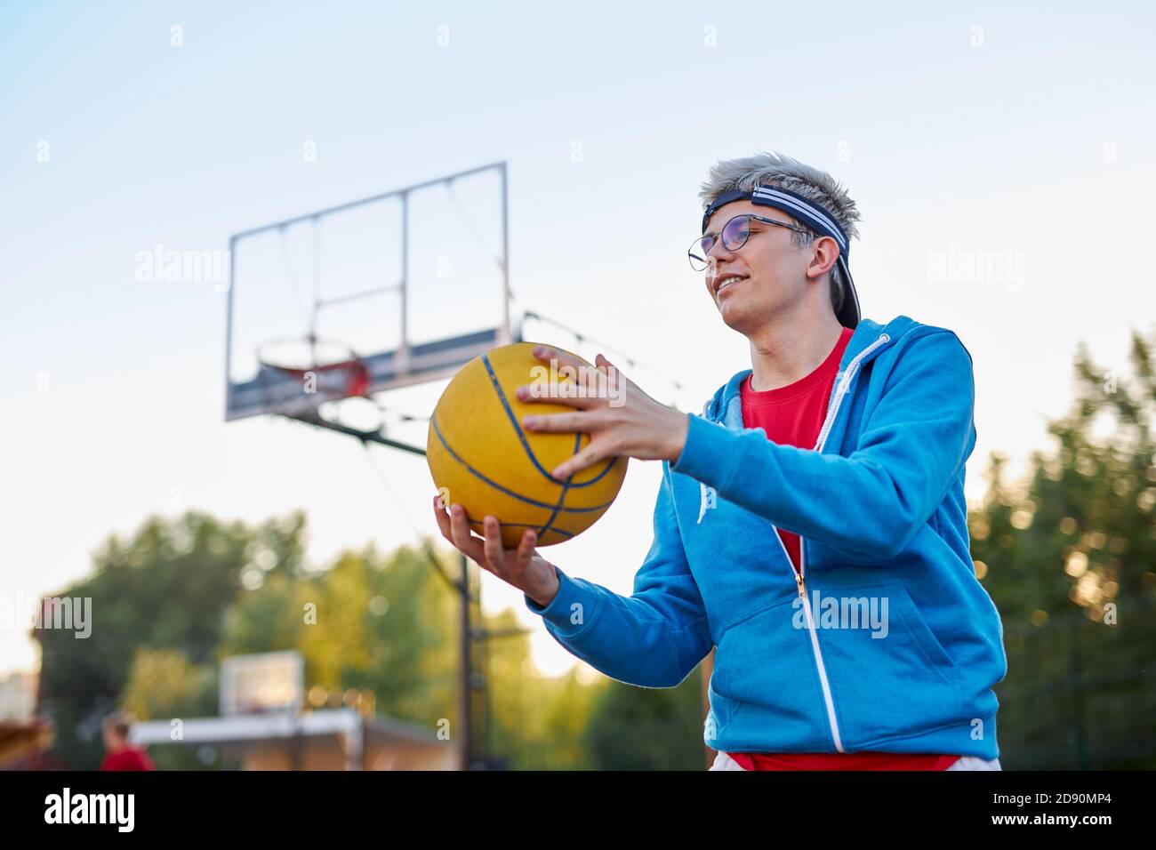 young caucasian teen boy playing basketball, handsome guy in casual sportswear alone at basketball playground, practice Stock Photo