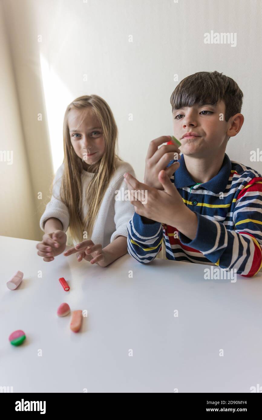 Children eating candy at the dining table while you play Stock Photo