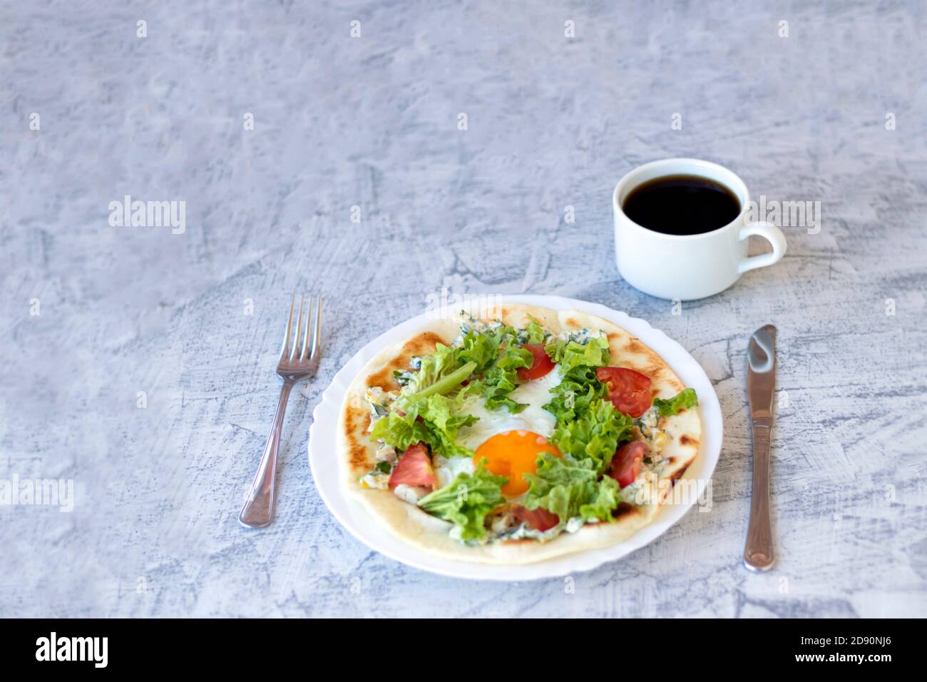 Italian breakfast with coffee. Piadina with egg, tomatoes and salad. Delicious breakfast served on textured table. Soft focus Stock Photo