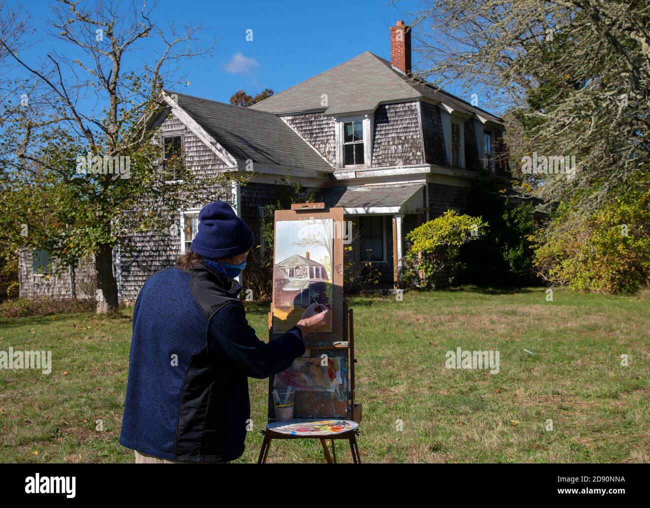 An artist at work painting the historic Fuller Farmhouse in Barnstable, Massachusetts, USA on a late fall morning Stock Photo
