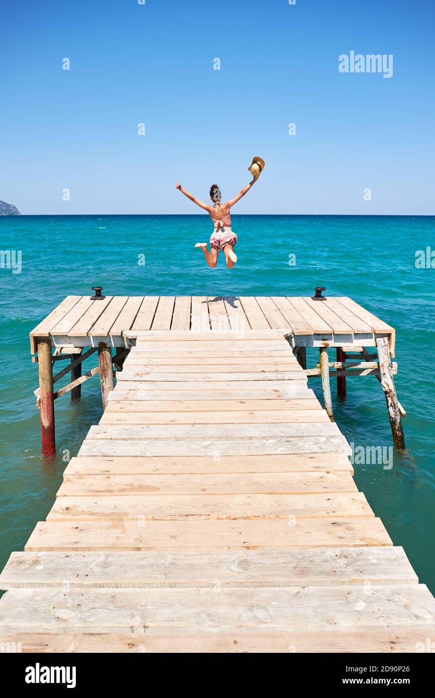 girl with hat jumping on a wooden wharf Stock Photo Alamy