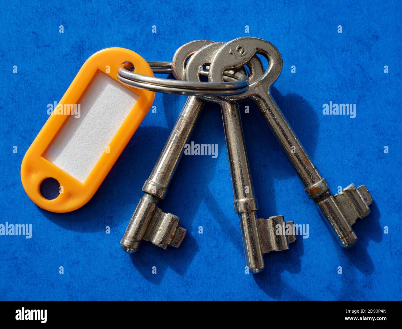 Closeup of three old matching steel door keys from the same lock, on a