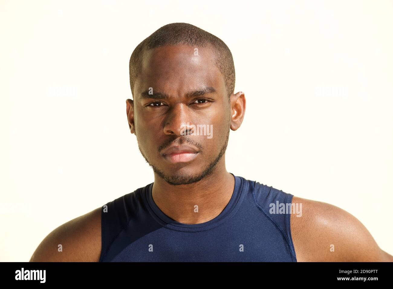 Close up front portrait of serious young black man against white ...