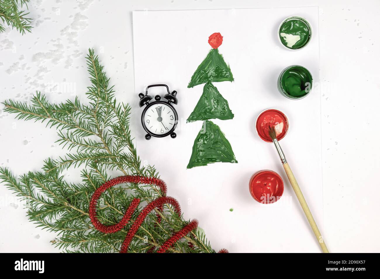 kids drawing, christmas tree and alarm clock with branches of christmas  tree and paints on a