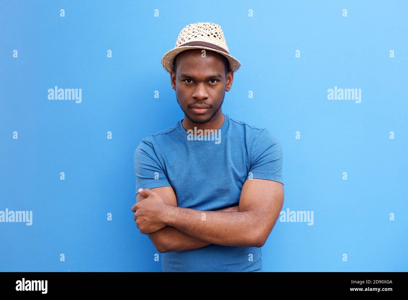 Portrait of cool young black guy with hat posing with arms crossed