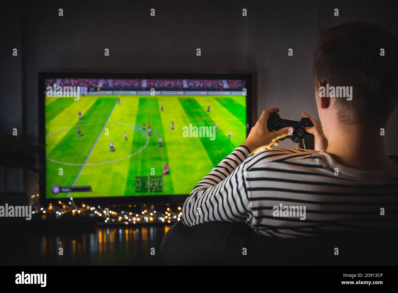 Young hipster man playing video game football soccer on console. gamer guy  with gamepad controller holding Wireless joystick sitting on pouf at night  Stock Photo - Alamy