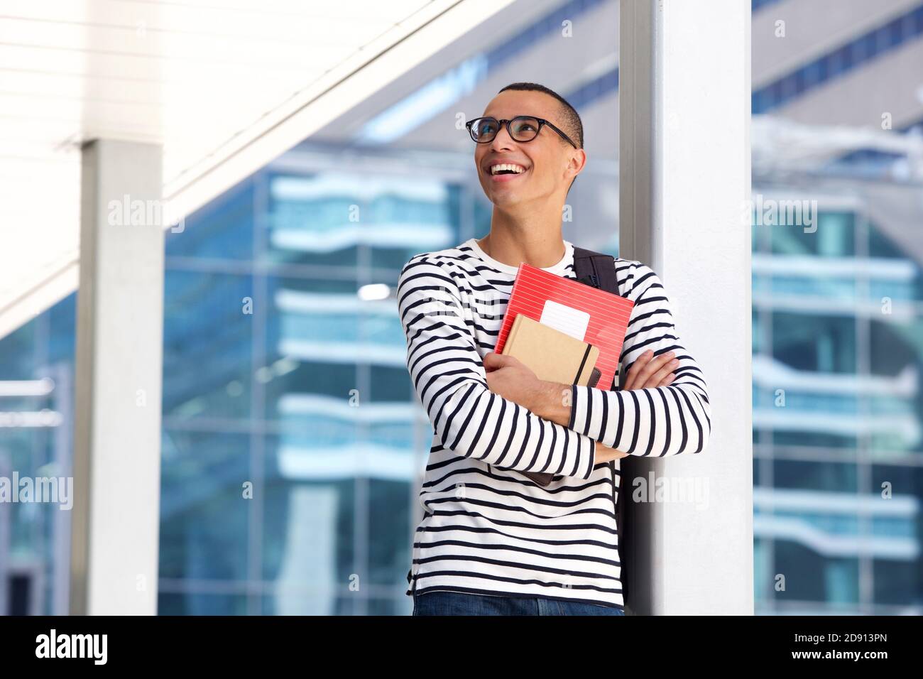 Portrait of happy male college student with glasses and books standing ...