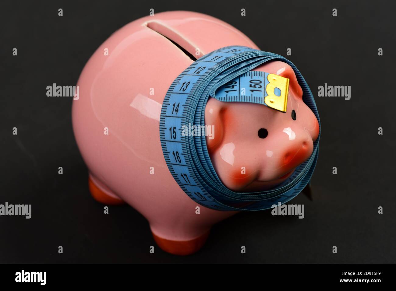 Measuring tape wrapped around piggy bank or money box on black background. Savings and financian diet concept Stock Photo