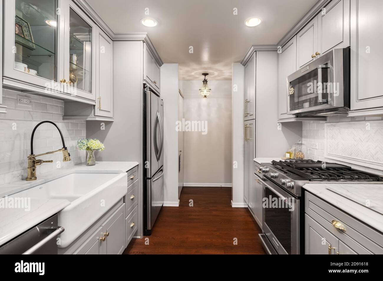 A renovated with kitchen with grey cabinets, gold hardware / faucet,  hardwood floors, and a small chandelier hanging from the ceiling Stock  Photo - Alamy