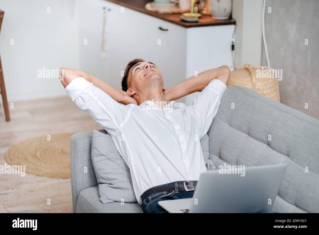 young man with a laptop is relaxing in the living room . Stock Photo