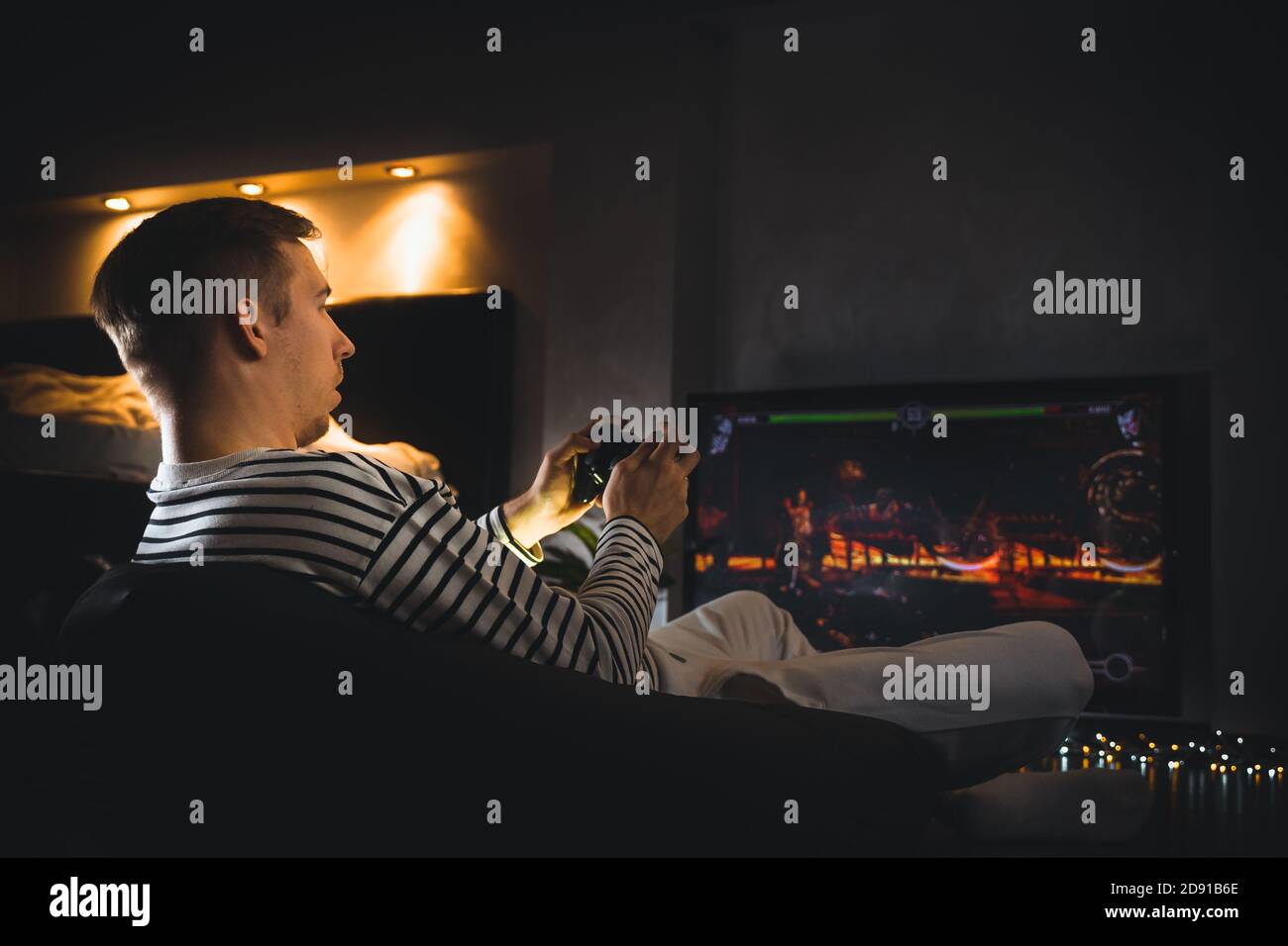 Young hipster man playing video game football soccer on console. gamer guy  with gamepad controller holding Wireless joystick sitting on pouf at night  Stock Photo - Alamy