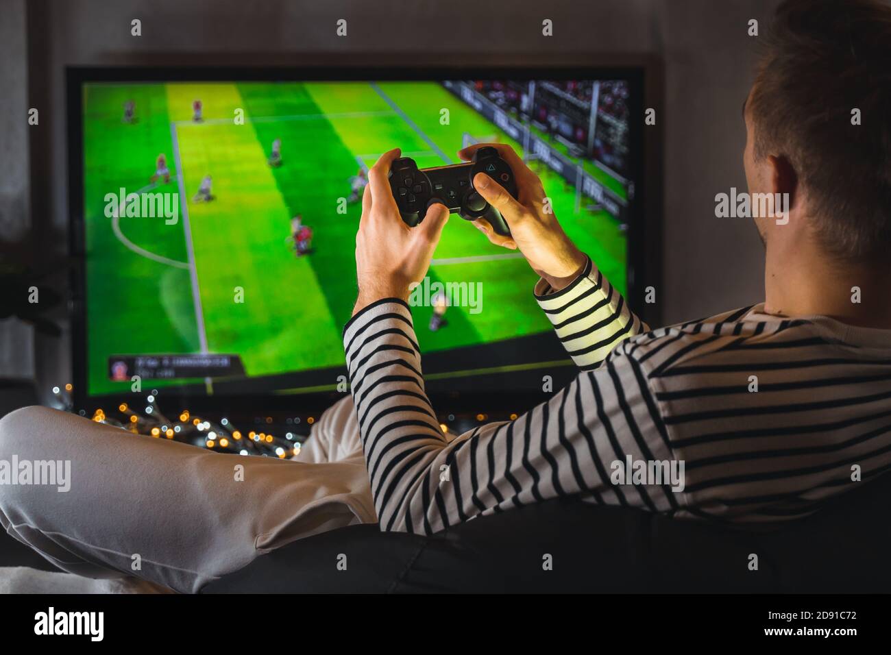 Young hipster man playing video game football soccer on console. gamer guy  with gamepad controller holding Wireless joystick sitting on pouf at night  Stock Photo - Alamy