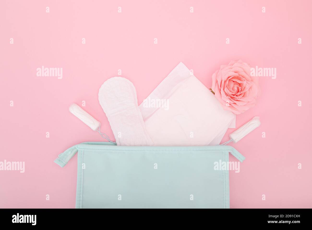 Sanitary pads and tampons coming out of a cosmetic bag on a pink