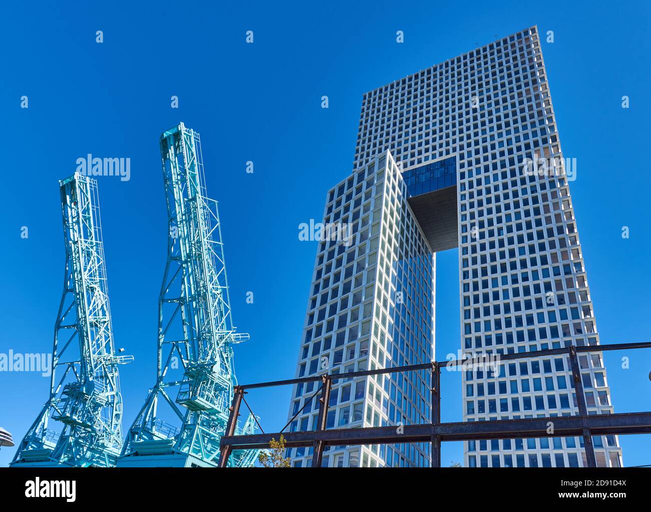 Cranes from the old Domino Sugar Factory in Domino Park rise next to a contemporary 45-story mixed use building Stock Photo