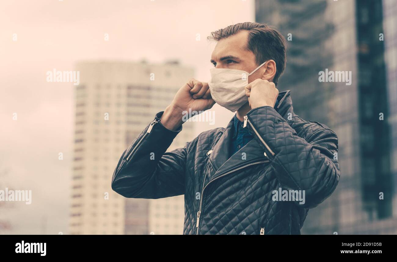 Man Using Protection young man putting on a protective mask standing on the street Stock ...