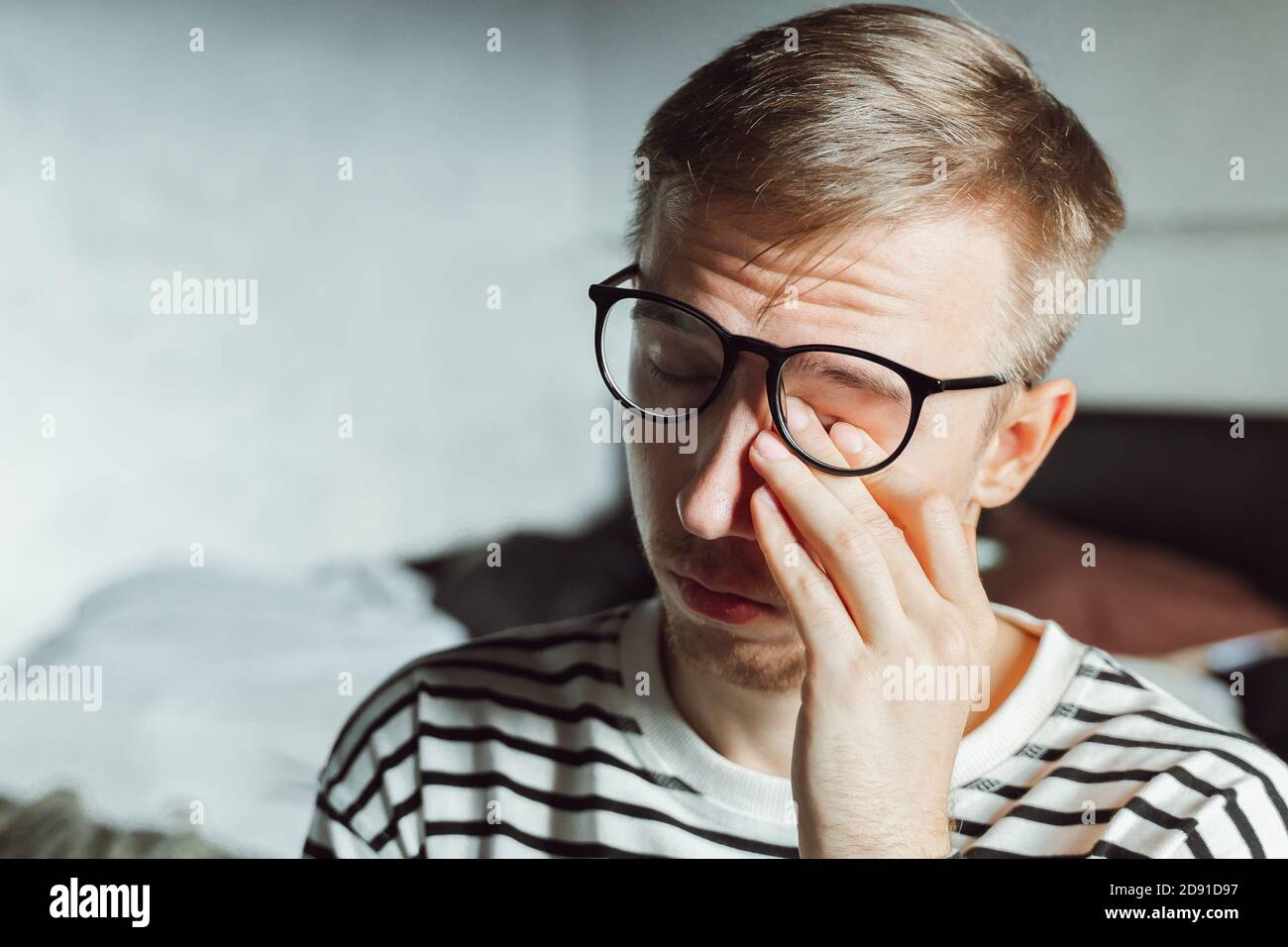 Tired man taking off glasses rubbing dry irritated eyes to relieve pain