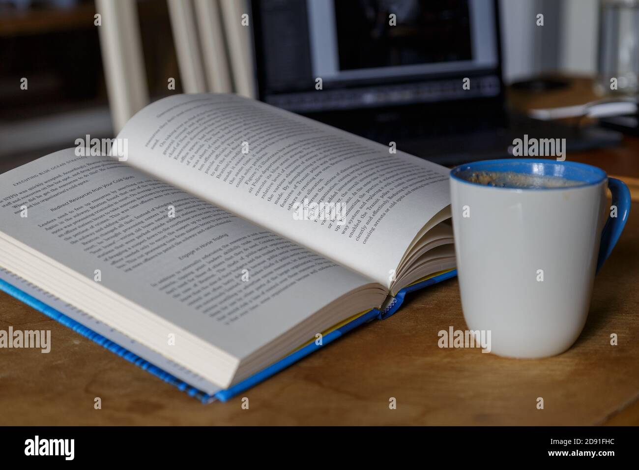 Multitasking reading drinking coffee working on laptop Stock Photo