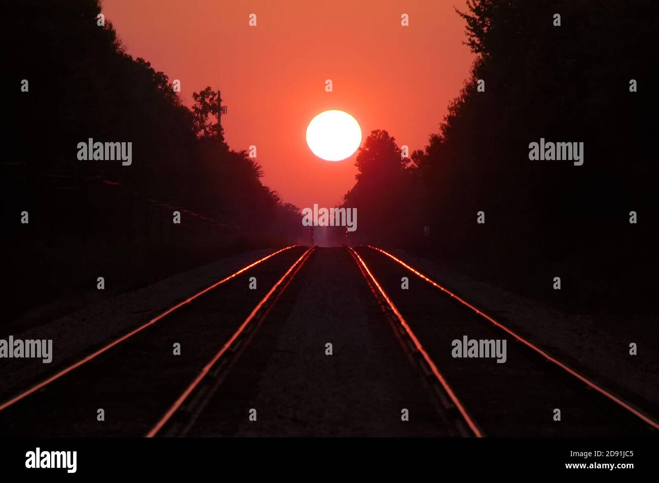 A double set of railroad tracks lead to infinity and a firey sunset Stock Photo
