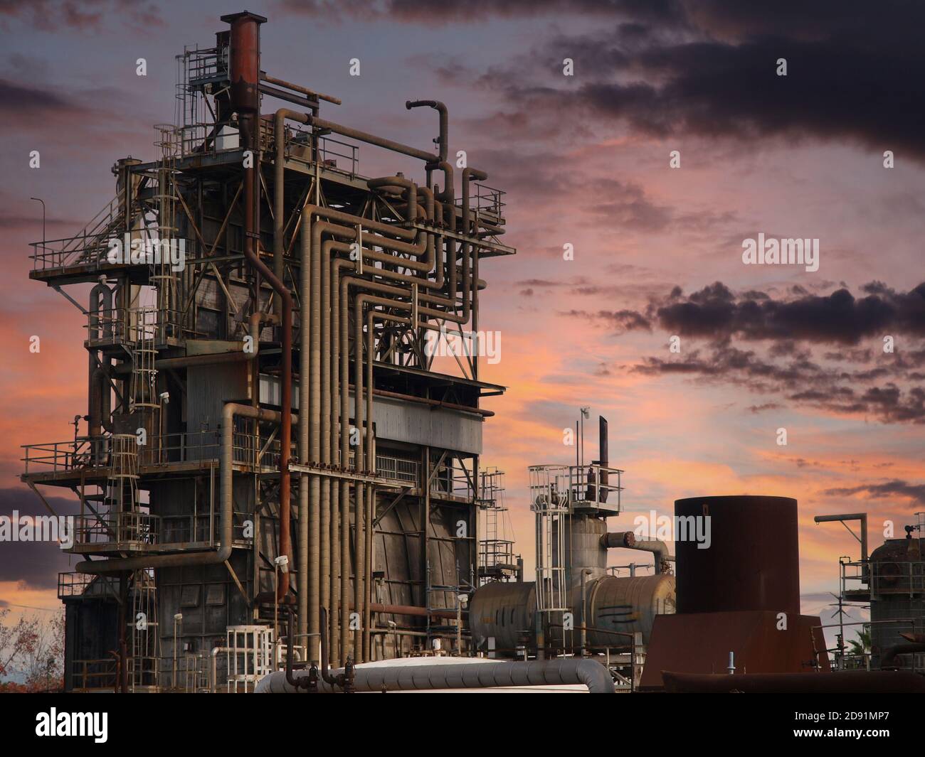 View of old rusty closed oil refinery tower with sunset sky. Stock Photo
