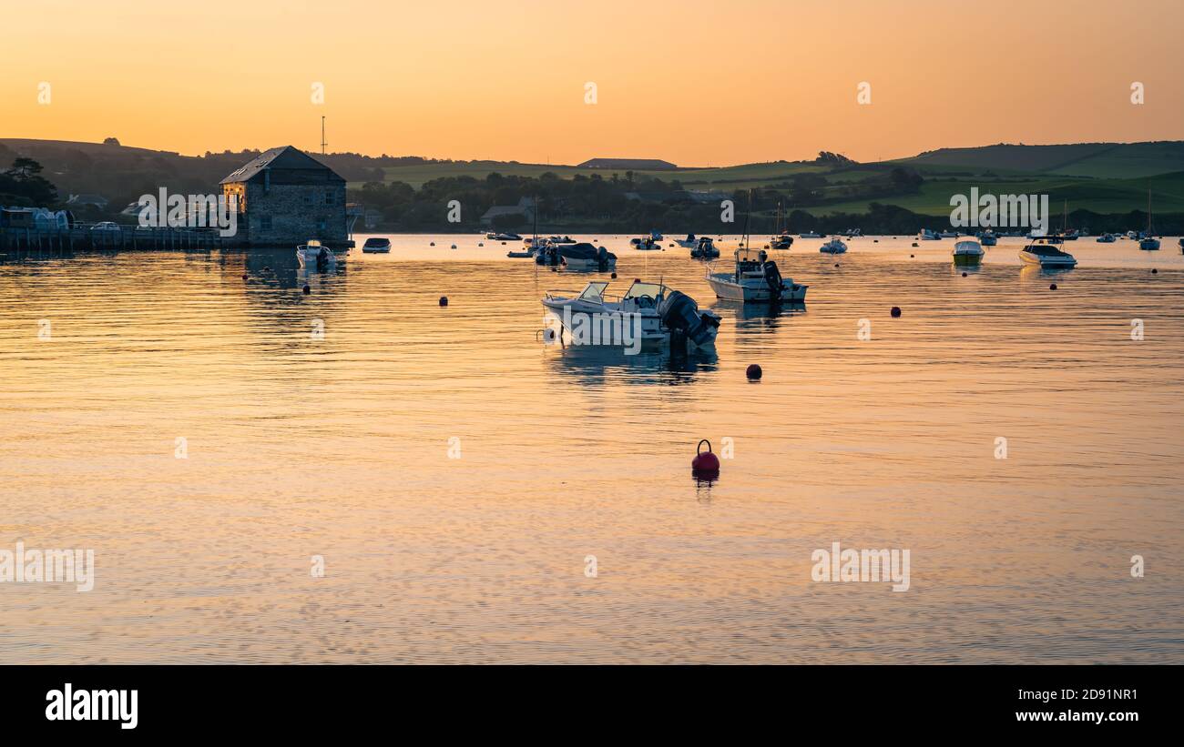 Rock Sailing and Waterski Clubhouse at dawn with sunrise reflected on the calm water with boats at moorings. Stock Photo