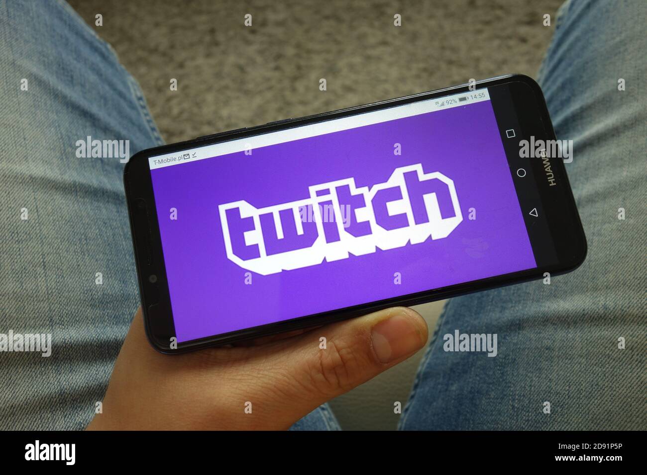 Man holding smartphone with Twitch video live streaming service logo Stock Photo