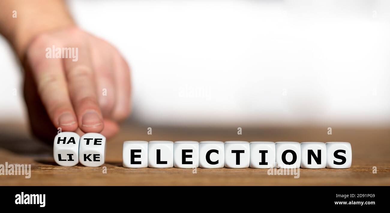 Hand turns dice and changes the expression 'like elections' to 'hate elections'. Stock Photo