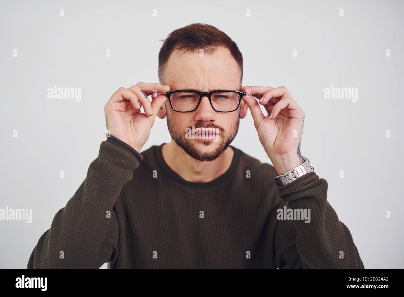 Young guy in sunglasses standing indoors against white background Stock
